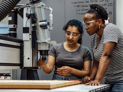 Two students work with building tools.